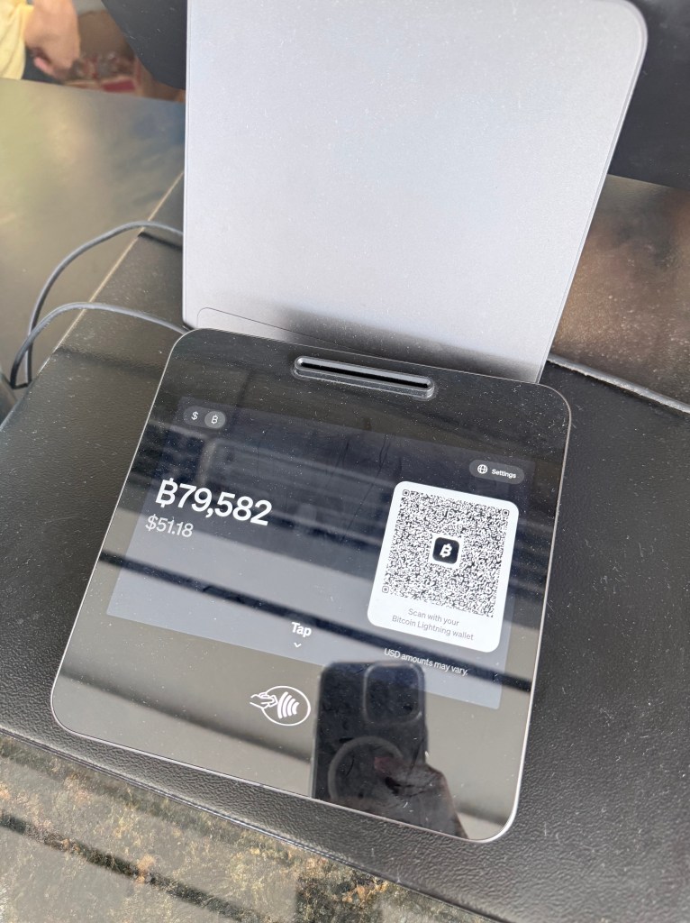 A digital payment device displaying a QR code for Bitcoin transactions, with a balance of B79,582 and an equivalent of $51.18.